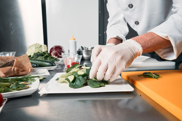 Closeup of the hand of a cook. Cook cuts greens for salad. Chef cooks in a professional kitchen
