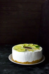 sweet white buttercream round cake with sliced lime against a dark background