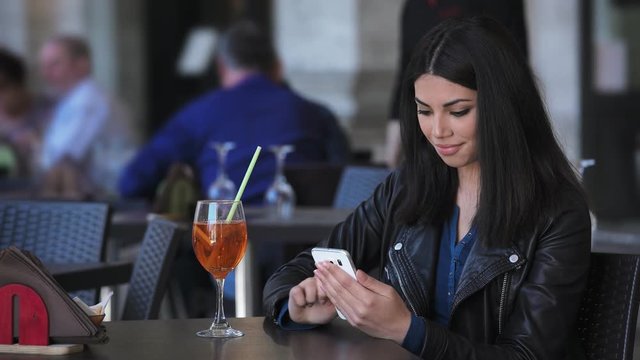 Smiling pretty asian woman using smartphone at restaurant