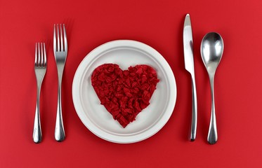 Servizio di tavolo con quore rosso di carta fatto a mano nel piatto bianco  di plastica,sul sfondo rosso