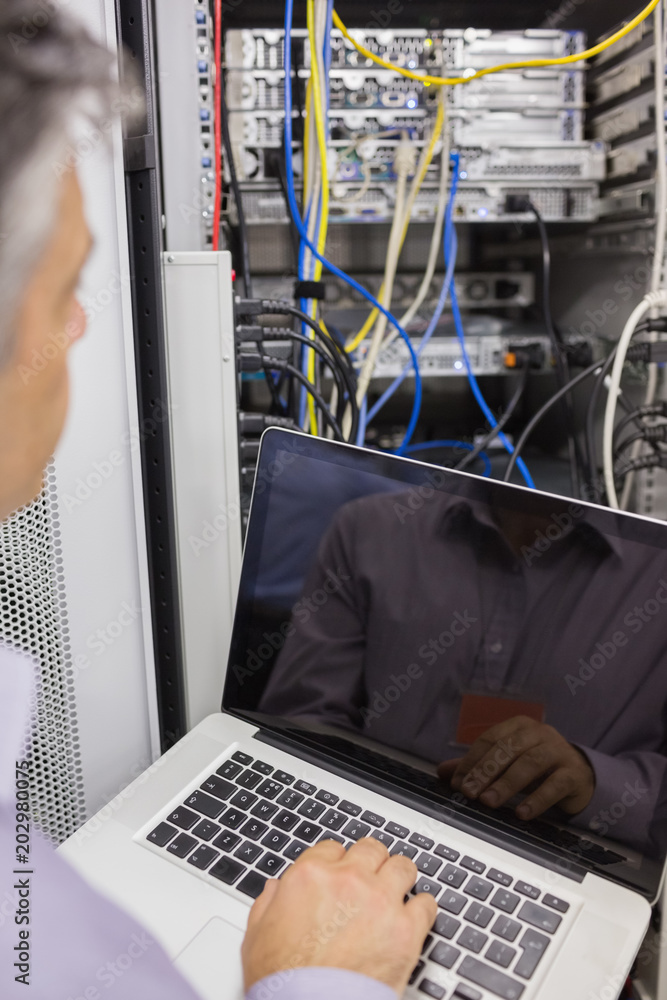 Poster Man sitting with a laptop in front of a server