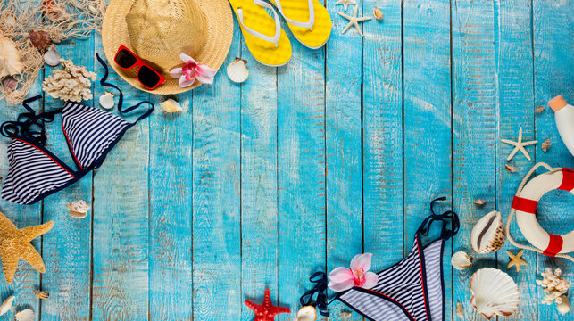 Beach accessories placed on blue wooden planks, top view.