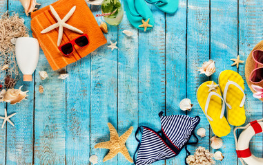 Beach accessories placed on blue wooden planks, top view.