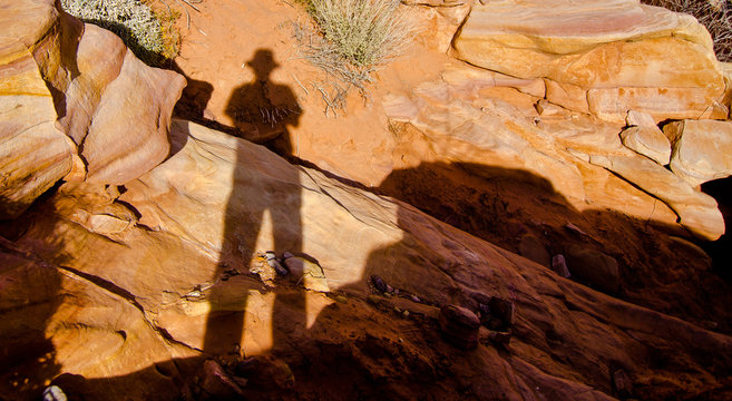 Shadow of man in fedora against desert rocks