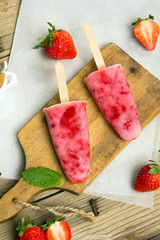 Fresh homemade strawberry ice cream on wooden background. Organic and vegan popsicles