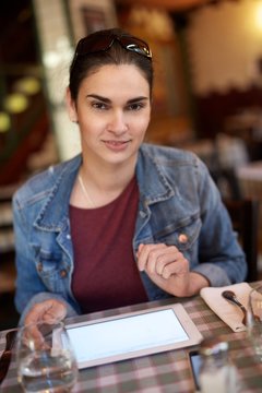 Smiling woman using tablet in restaurant