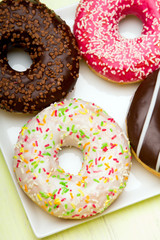 Cup of coffee and tasty donuts with icing and chocolate on green wooden background, copy space