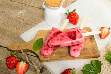 Fresh homemade strawberry ice cream on wooden background. Organic and vegan popsicles