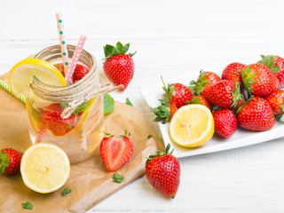 Mineral  water with fresh strawberries, lemon  and mint in jar on a white wooden background, copy space