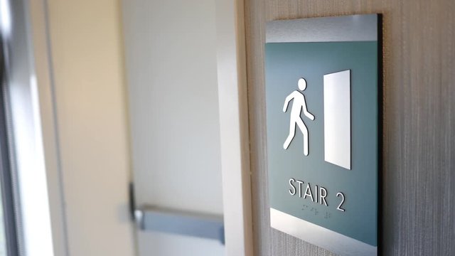 Man enters a stairwell in modern building - sign close up