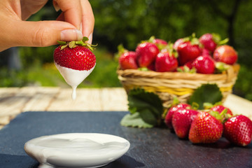 strawberries with cream on stone background, delicious first class organic fruit as a concept of summer vitamins