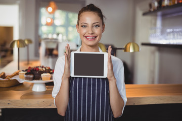 Portrait of waitress holding digital tablet at counter