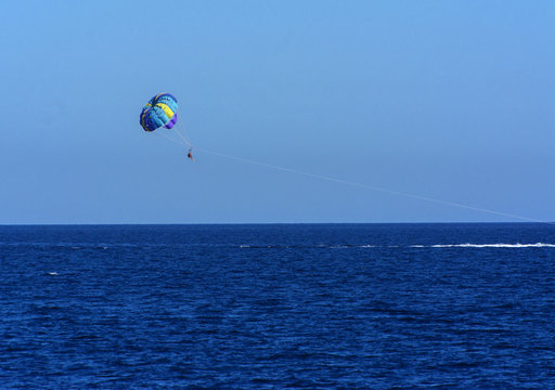 Parachute over the sea against a blue sky and clear sea water, towing on a boat. Riding a parachute behind a boat. The concept of travel, release, summer, rest.
