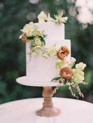 Close-up of wedding cake decorated with flowers on cake stand