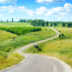 Winding asphalt road among fields in countryside.