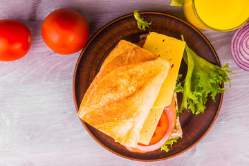 Delicious homemade sandwich with ham, cheese, tomatoes and lettuce on plate - top view