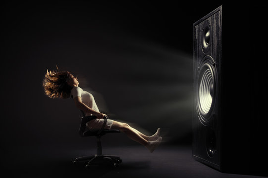 The powerful sound set back an office cheir with young woman.