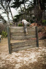 Soldier climbing wooden wall in boot camp