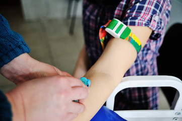 Doctor making blood analysis young girl patient. Blood sampling from a vein on the background of the clinic