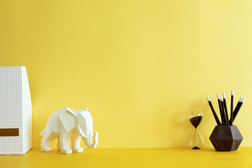 Yellow interior with elephant figure, hourglass and office accessories. Creative space with yellow...