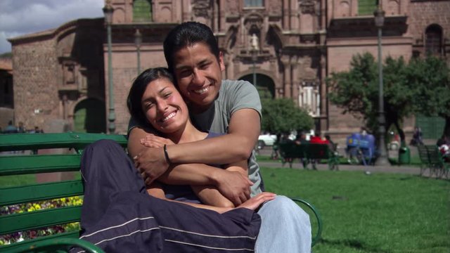Couple embracing on Plaza de Armas park bench in Cusco, Peru