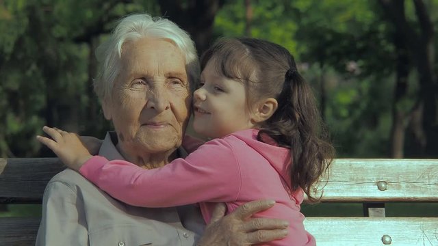 Grandmother with granddaughter. Elderly woman with a child in the park.