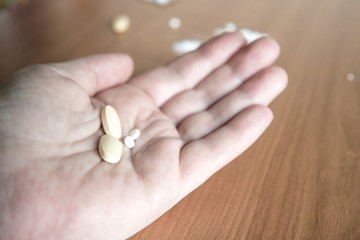 Person holding hand open with different presciption drugs for abuse.