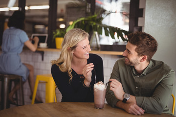 Smiling couple with fresh dessert while sitting at coffee shop