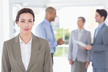 Businesswoman smiling at camera while her colleagues discussing 