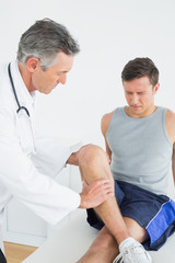 Obraz premium Displeased young man getting his leg examined