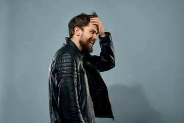 a man in a leather jacket touches his head