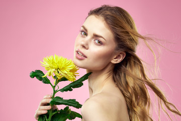 woman with a yellow flower on a pink background tilted her head back