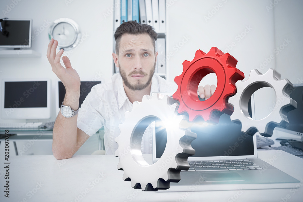 Poster white and red cogs and wheels against confused computer engineer looking at camera with laptop