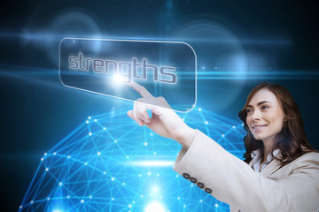 Businesswoman pointing to word strengths against glowing sphere on black background