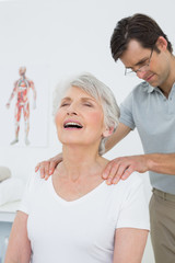 Male physiotherapist massaging a senior womans shoulders