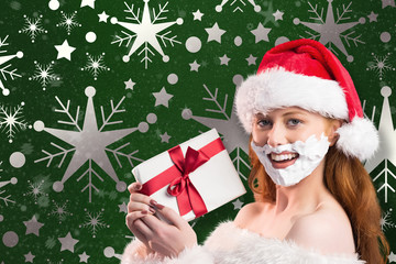 Festive redhead in foam beard holding gift against snowflake wallpaper pattern