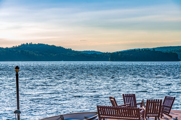 Naklejka premium Wooden chairs on a dock which is lake side.