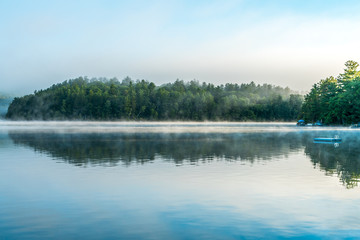 Early morning mist lifts off a small, reflective lake