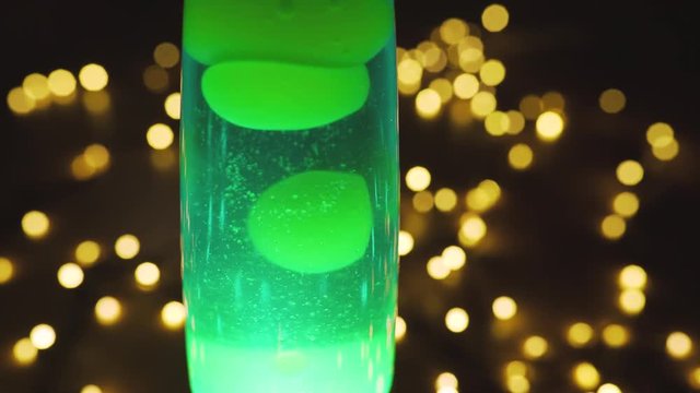 4k lava lamp retro vintage hippie abstract background, green wax moving floating. Bokeh of the garlands in background