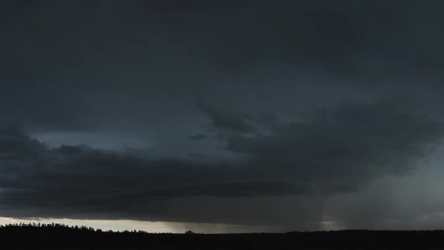 Low gray upslope thunderstorm pours rain on a line of dark hills, time lapse