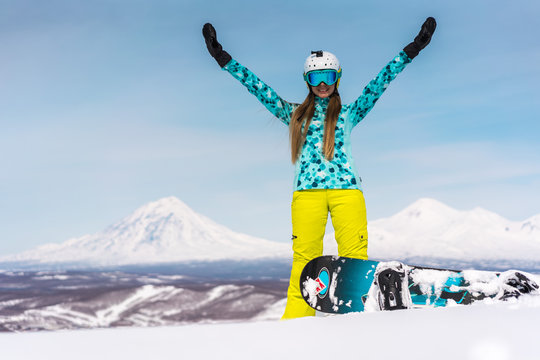 Happy young woman with snowboard in front of volcanos