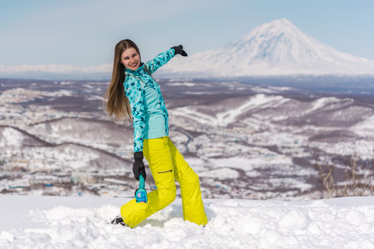 Happy young woman with snowboard in front of volcanos