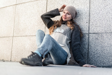 Young woman sitting alone next to granite wall