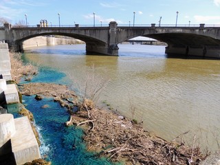 Pedestrian bridge in White River State Park Indianapolis Indiana with muddy and vivid blue water mixing