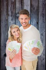 Attractive couple flashing their cash against grey wooden planks