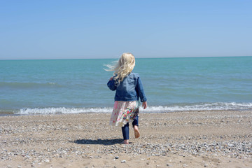 Little girl walking on beach in springtime