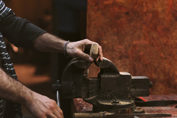 Man working in carpentry workshop. He fixes in grip a wooden ax handle. Men at work. Hand work.