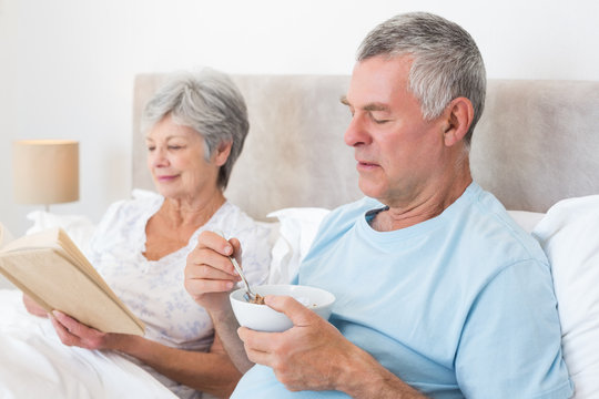 Senior couple with cereal bowl and book