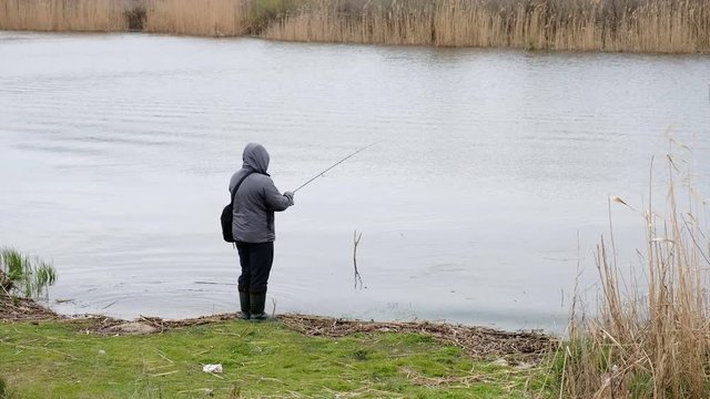 Fishing in river. A fisherman with a fishing rod on the river bank. Man fisherman catches a fish. Fishing, spinning reel, fish, Breg rivers. - The concept of a rural getaway. 