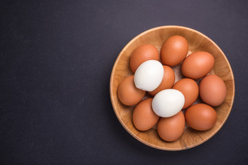 Fresh egg and boiled egg without shell. Top view on black stone